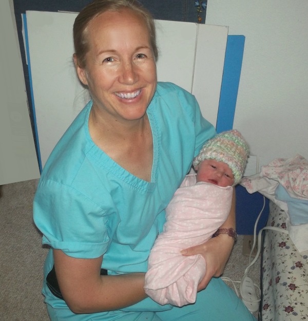 Tara Stephens, Midwife and Owner of Beautiful Births Homebirth Midwifery Practice in Colorado Springs, CO holding new baby girl in pink  blanket