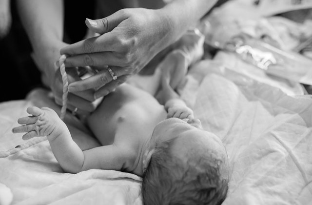  Tara Stephens, Midwife and Owner of Beautiful Births Homebirth Midwifery Practice in Colorado Springs, CO cutting the umbilical cord off a newborn.