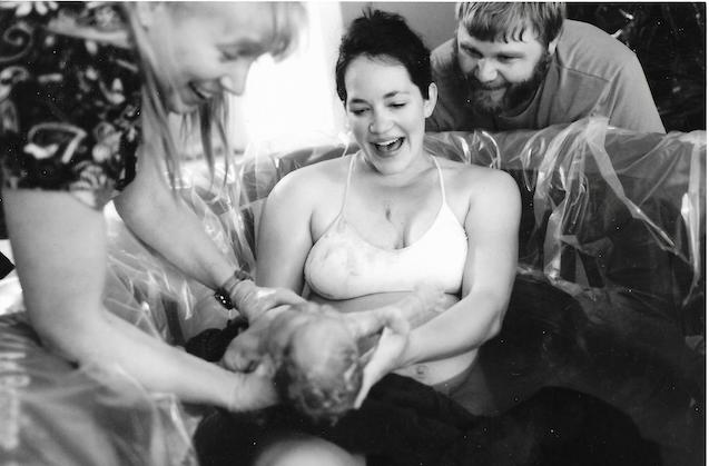 Tara Stephens, Midwife and Owner of Beautiful Births Homebirth Midwifery Practice in Colorado Springs, CO assisting couple deliver a newborn baby in a water birth